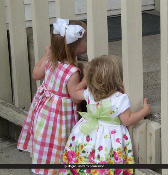 image of two girls looking through a fence outside