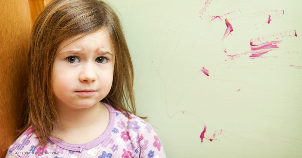 young girl standing in front of a wall with magenta hand paint