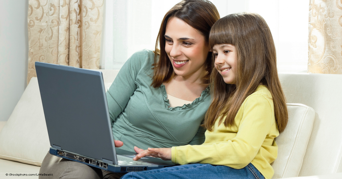 mom and daughter sitting on couch and using a computer