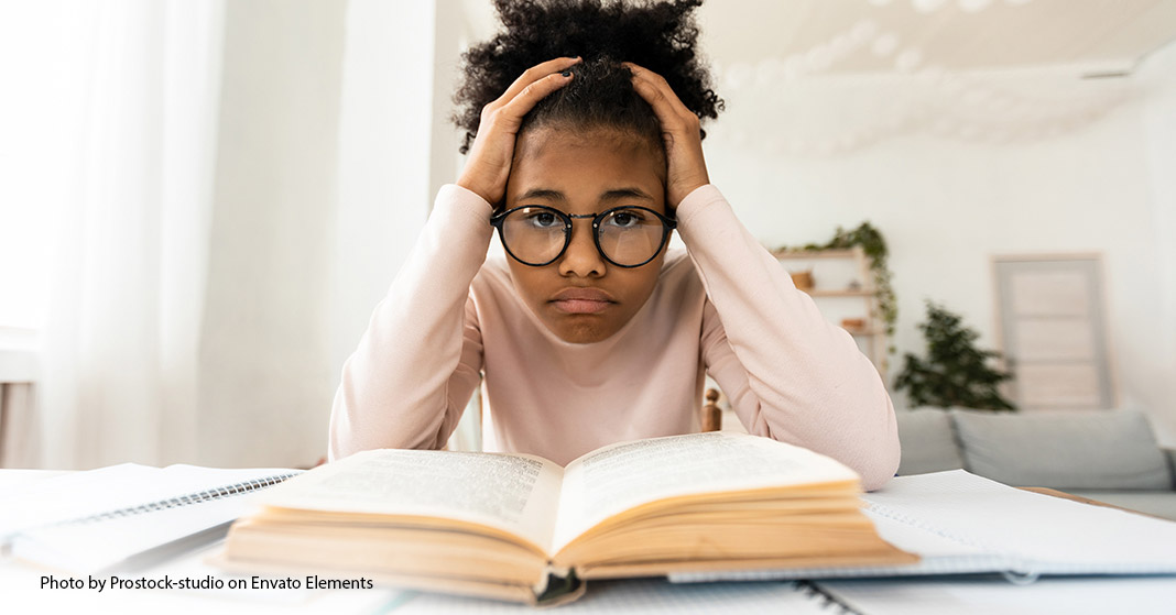 girl with glasses sitting over book looking disgruntled