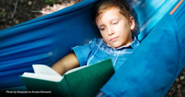 child sitting in hammock reading book