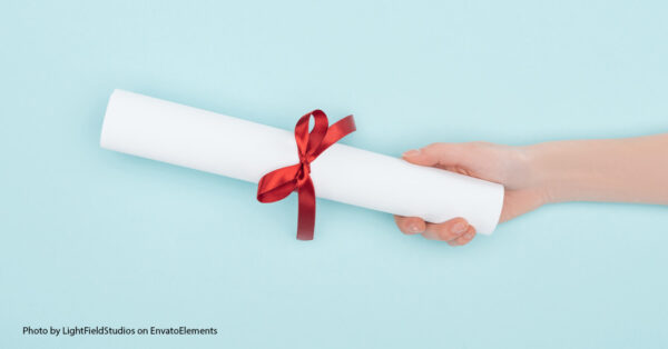 person holding a paper wrapped with a ribbon